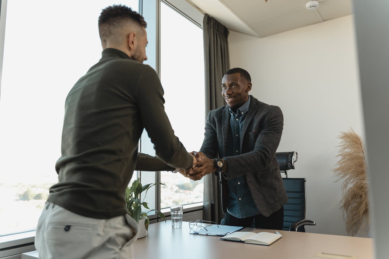 creative-03 Two businessmen exchanging a handshake during a professional meeting in a modern office setting.